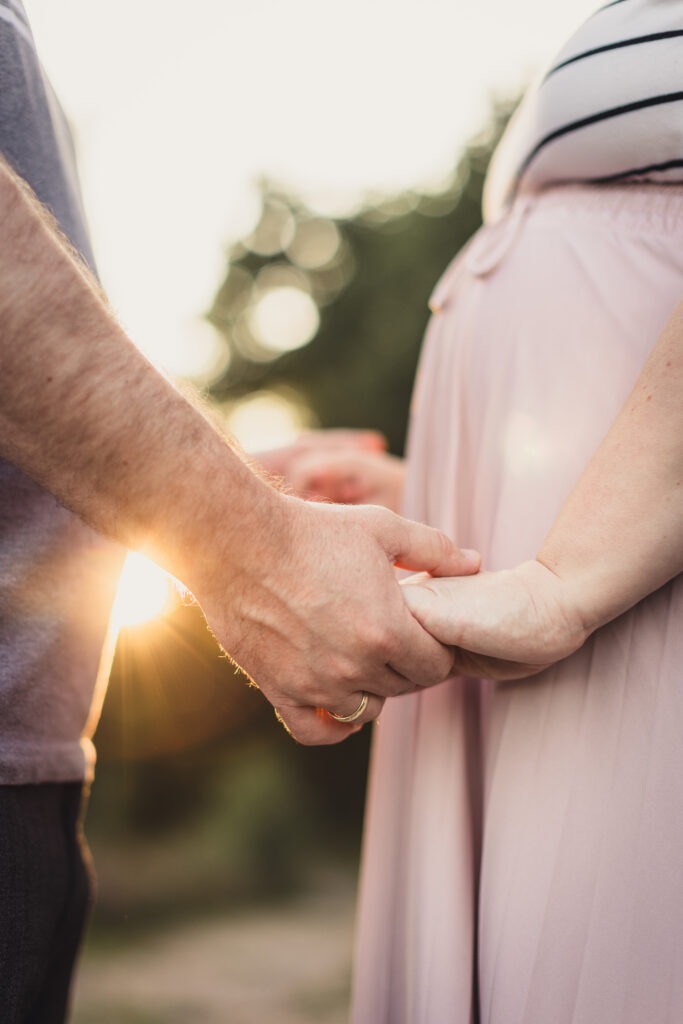 Babybauchfotos Kiel – Paar hält sich liebevoll an den Händen