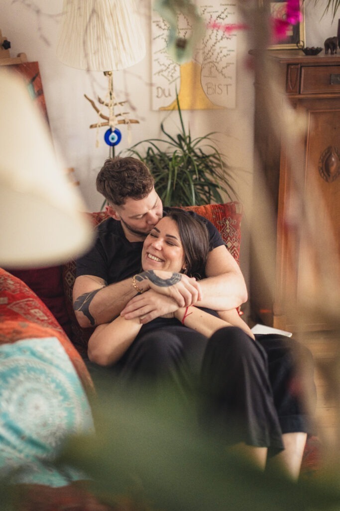 Babybauchfotos Hannover – Paar kuschelt liebevoll auf dem Sofa