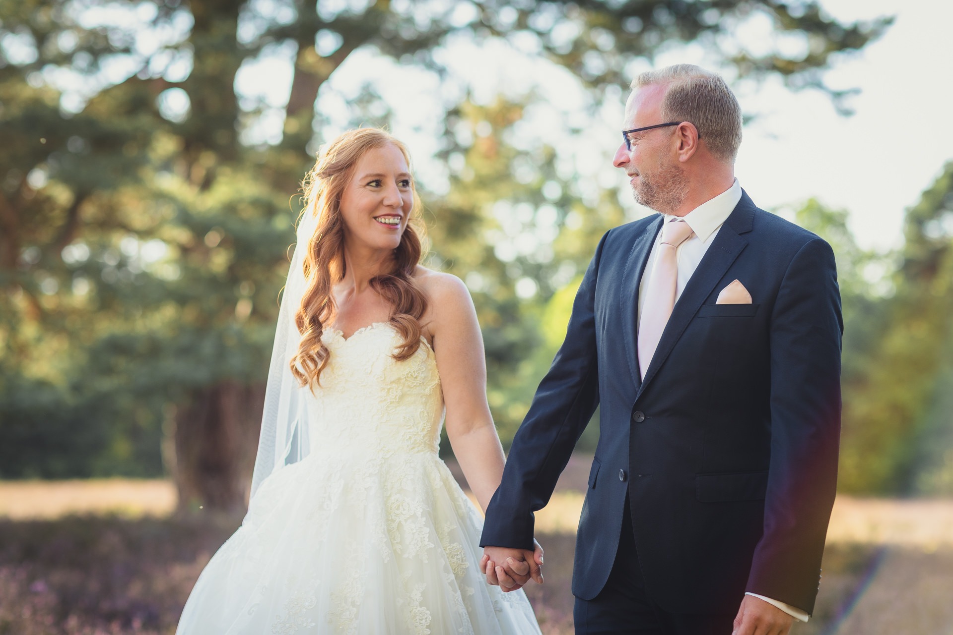 Hochzeitsfotografie Hamburg - Brautpaar geht Hand in Hand durch die Heide